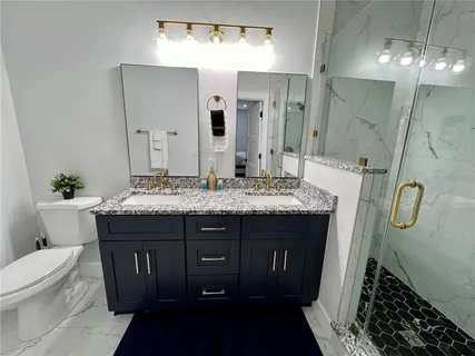 a bathroom with a granite countertop sink a toilet and a mirror