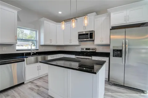 a kitchen with granite countertop a refrigerator sink and microwave