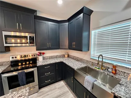 a kitchen with stainless steel appliances granite countertop a sink stove and microwave