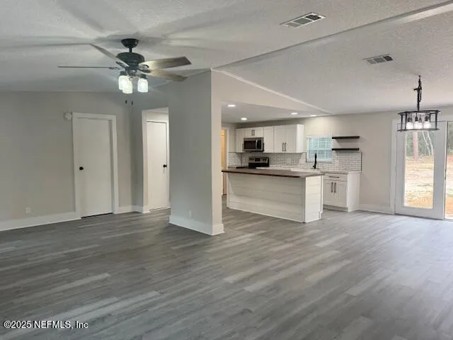 a view of a kitchen with a sink a refrigerator and wooden floor