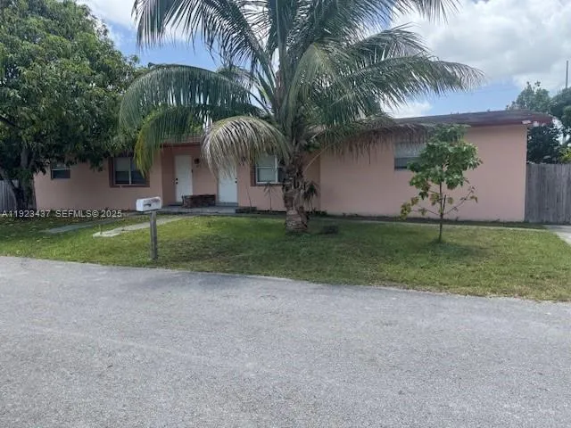 a view of a house with a yard and palm trees
