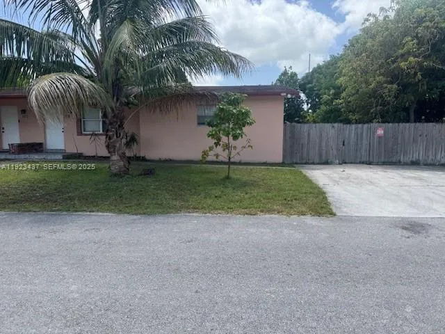 a view of a house with a yard and a palm tree