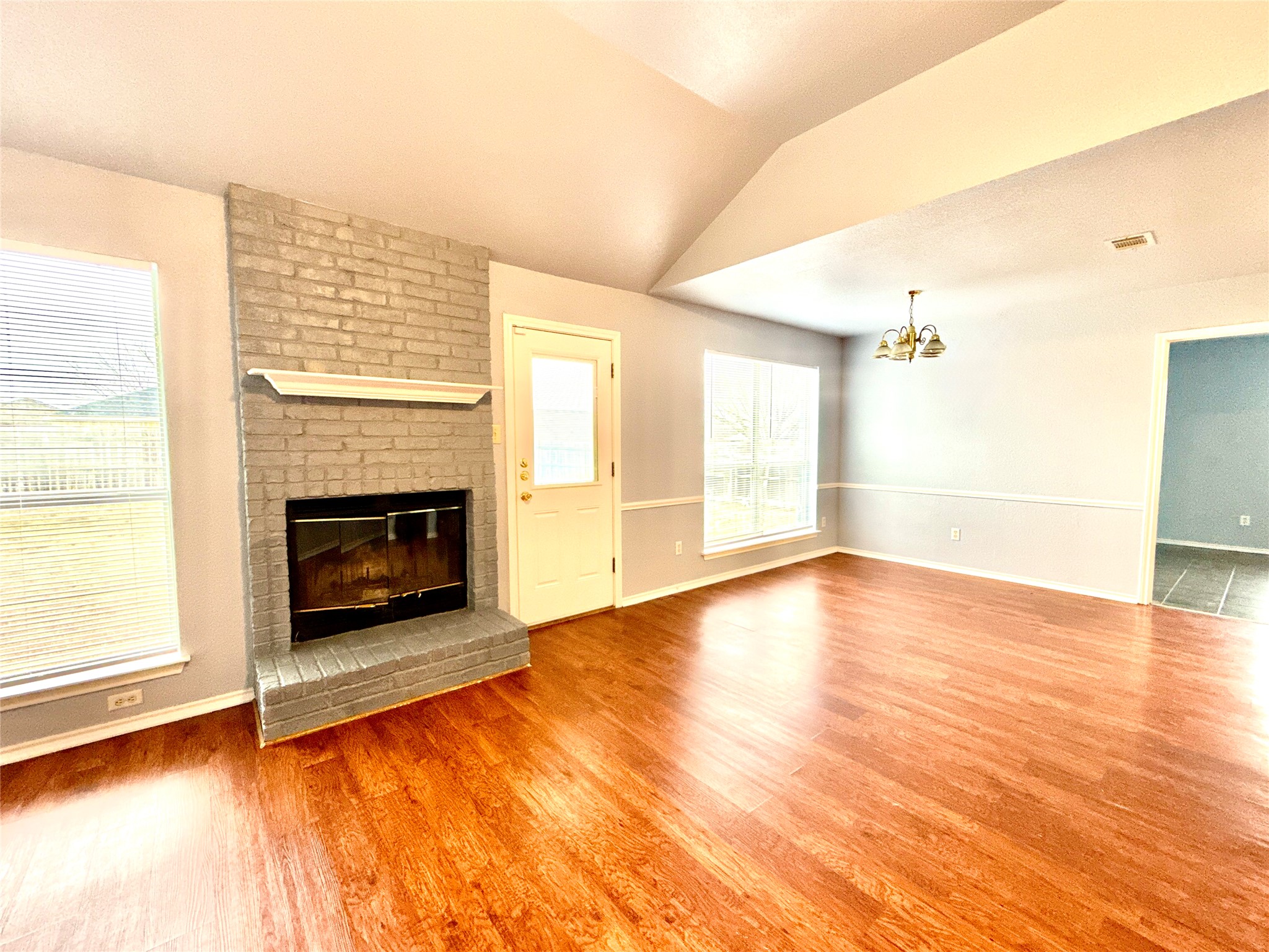 2703 Little Nolan Road Killeen, TX 76542 - Photo 2 of 11 Unfurnished living room featuring lofted ceiling, light wood-style flooring, a fireplace, and hanging lights