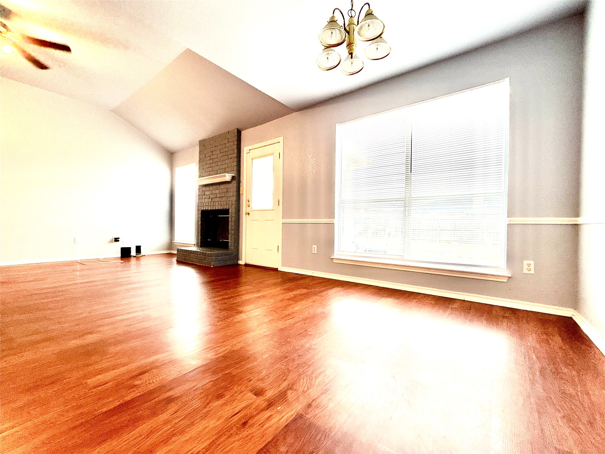 2703 Little Nolan Road Killeen, TX 76542 - Photo 4 of 11 Unfurnished living room with wood finished floors, a chandelier, vaulted ceiling, plenty of natural light, and ceiling fan