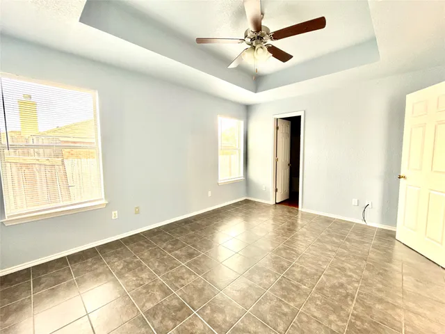 a view of an empty room with window and chandelier fan