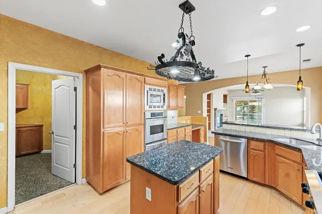 a kitchen with stainless steel appliances granite countertop a sink a refrigerator and a wooden cabinets