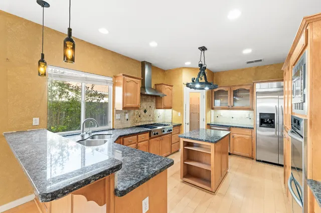 a kitchen with stainless steel appliances granite countertop a sink and a refrigerator