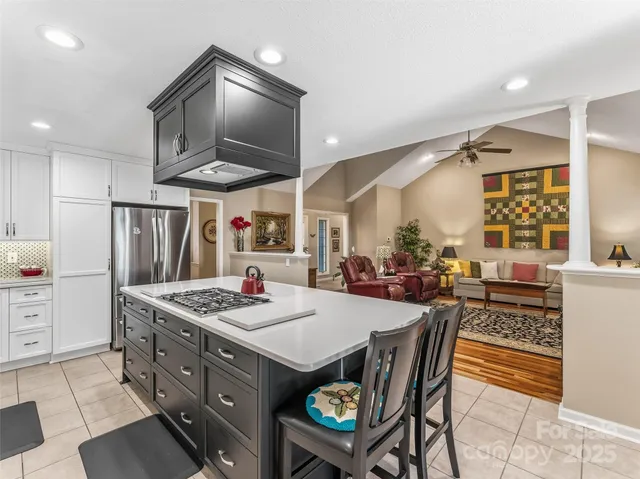 a kitchen with stainless steel appliances kitchen island granite countertop a stove a sink a dining table and chairs