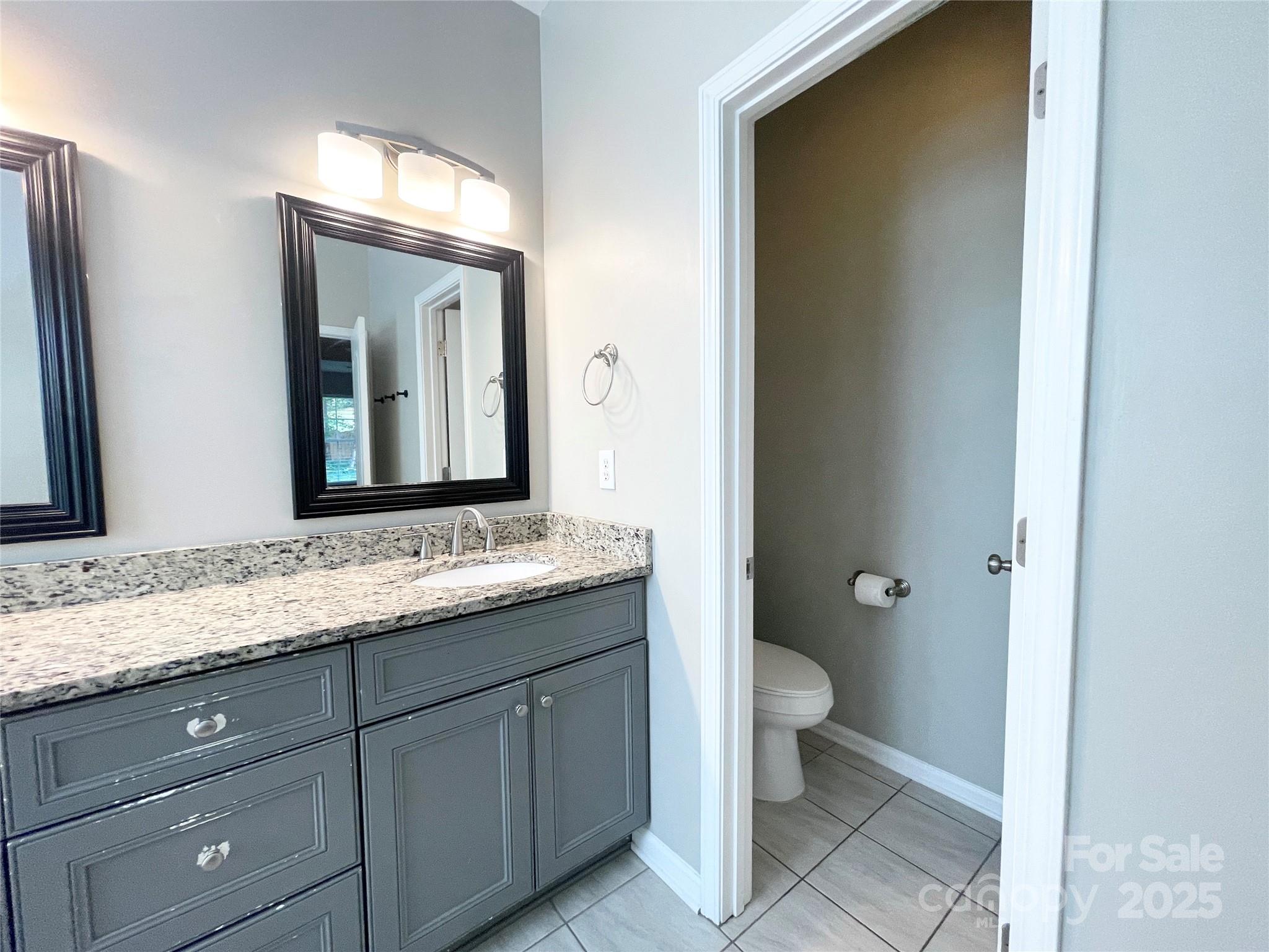 2834 Ritz Lane Matthews, NC 28105 - Photo 30 of 32 a bathroom with a granite countertop toilet sink and mirror