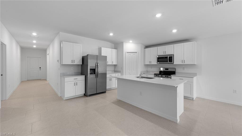 156 Peerless Street Lehigh Acres, FL 33974 - Photo 13 of 26 a kitchen with stainless steel appliances a refrigerator sink stove and microwave