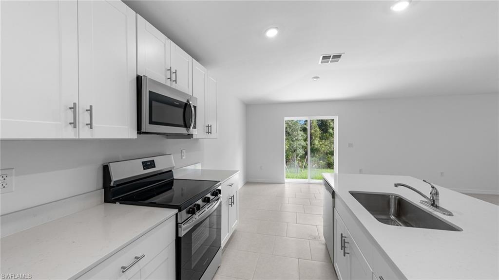 156 Peerless Street Lehigh Acres, FL 33974 - Photo 14 of 26 a kitchen with a sink a stove and cabinets