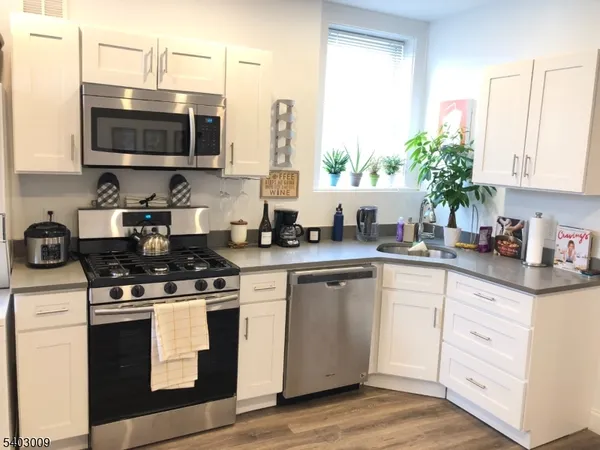 a kitchen with stainless steel appliances white cabinets a sink and a stove