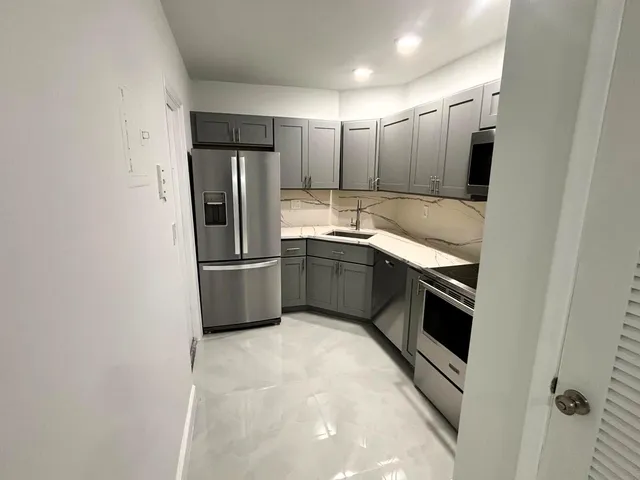 a kitchen with stainless steel appliances granite countertop a refrigerator a sink and a stove