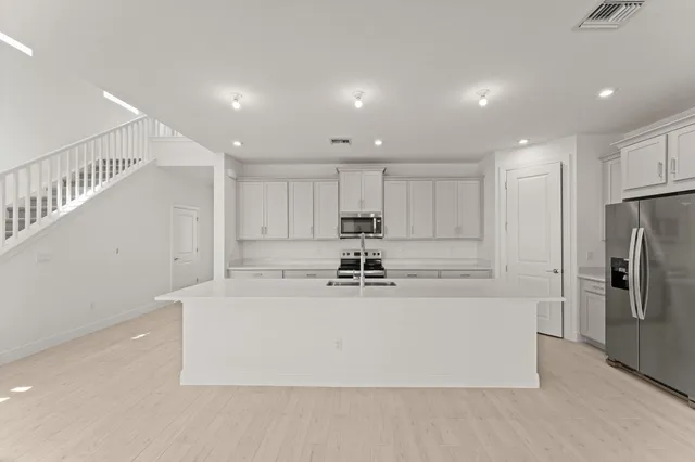 a view of kitchen with kitchen island stainless steel appliances sink refrigerator and microwave
