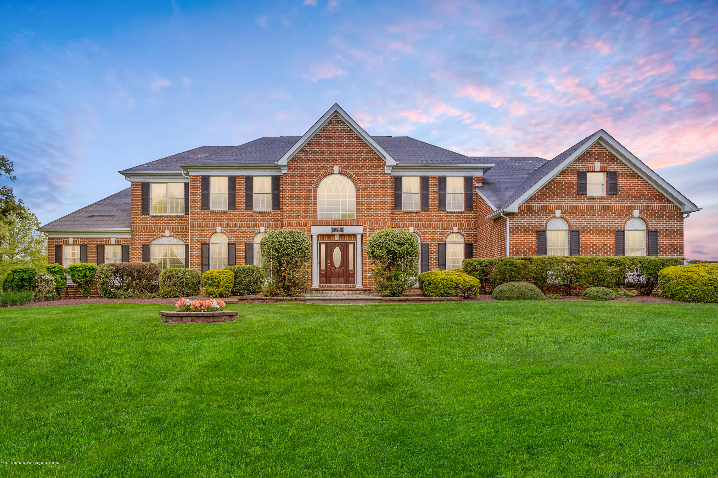 a front view of a house with a yard and trees