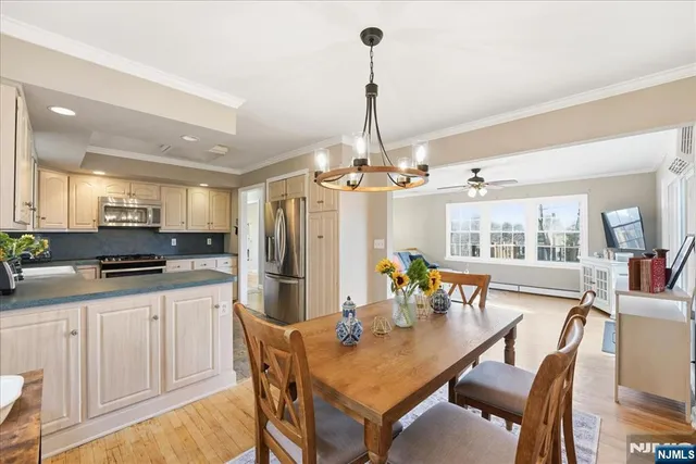a kitchen with stainless steel appliances a dining table chairs stove and refrigerator