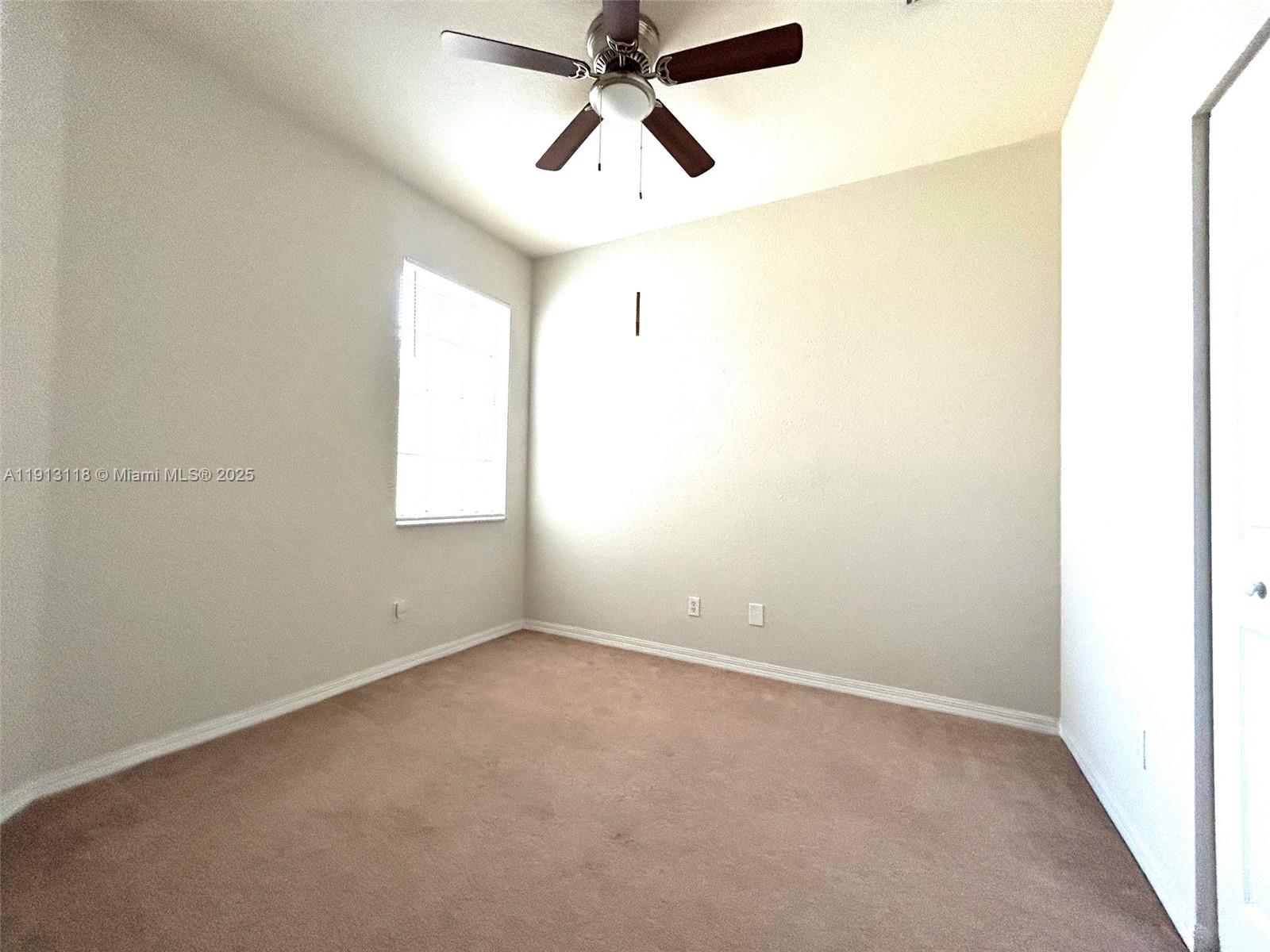 1560 Southeast Wilshire Place, Unit 103 Stuart, FL 34994 - Photo 23 of 33 an empty room with chandelier fan and windows