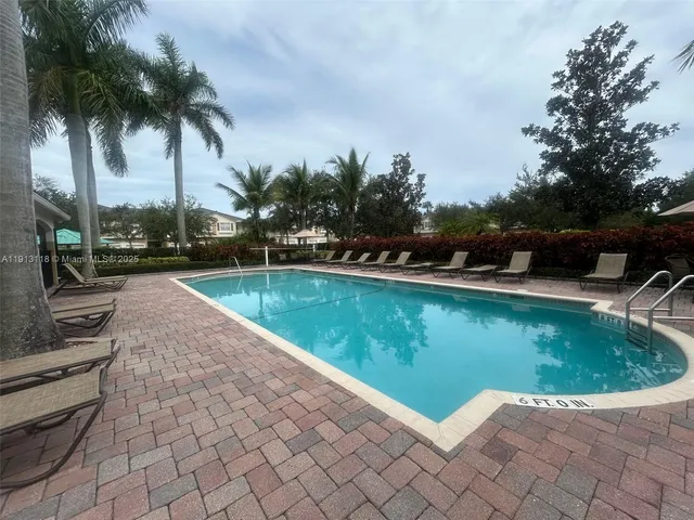 a view of a swimming pool with a yard and palm trees