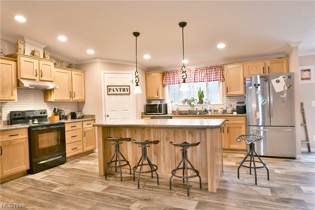 1570 Kale Adams Road Southwest Warren, OH 44481 - Photo 22 of 34 Kitchen featuring a kitchen island, light hardwood / wood-style flooring, and stainless steel appliances
