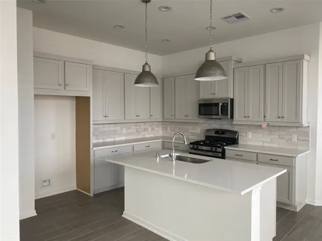 a kitchen with stainless steel appliances a sink a stove a microwave and cabinets
