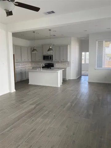 a kitchen with stainless steel appliances a white wooden cabinets and wooden floor