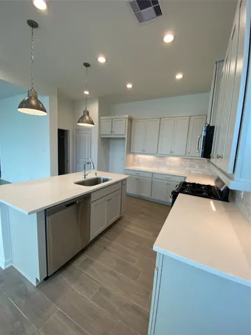 a large kitchen with kitchen island a sink a stove a refrigerator and a dining table with wooden floor