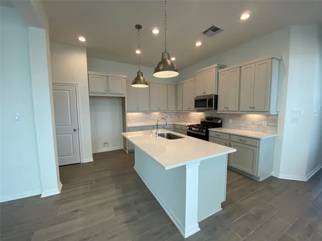 a kitchen with kitchen island a sink dishwasher stove and white cabinets with wooden floor