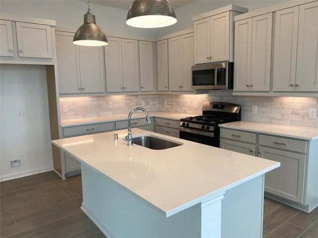 a kitchen with stainless steel appliances a sink a stove a microwave and cabinets