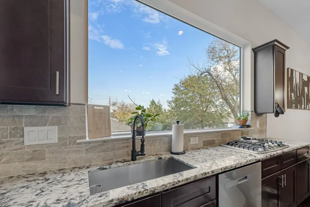 a kitchen with granite countertop a sink stainless steel appliances and cabinets