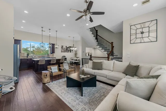 a living room with furniture kitchen view and a wooden floor