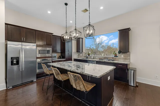 a kitchen with stainless steel appliances granite countertop a sink a stove a refrigerator and island