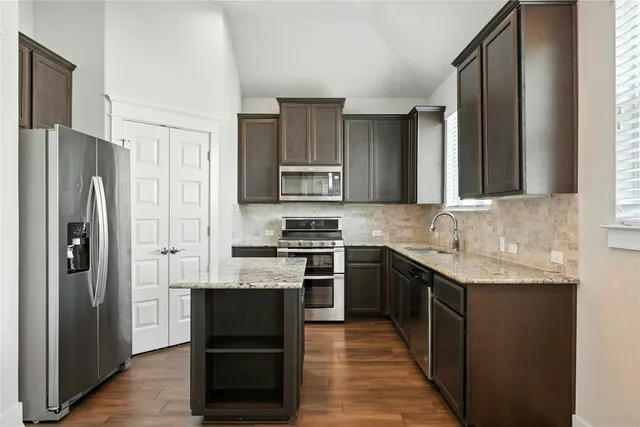 a kitchen with stainless steel appliances granite countertop a refrigerator and a stove top oven
