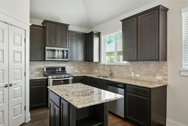 a kitchen with stainless steel appliances granite countertop a sink stove and microwave