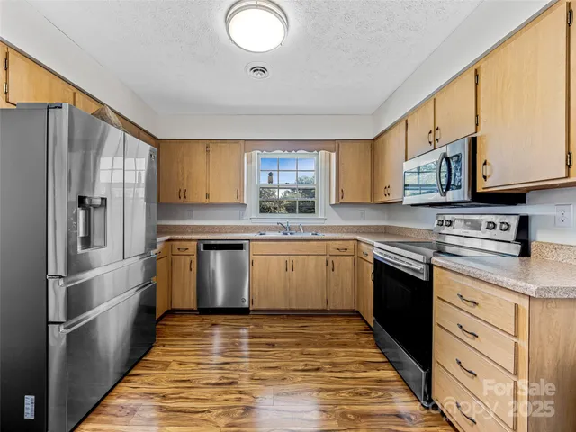 a kitchen with granite countertop wooden cabinets stainless steel appliances and a window