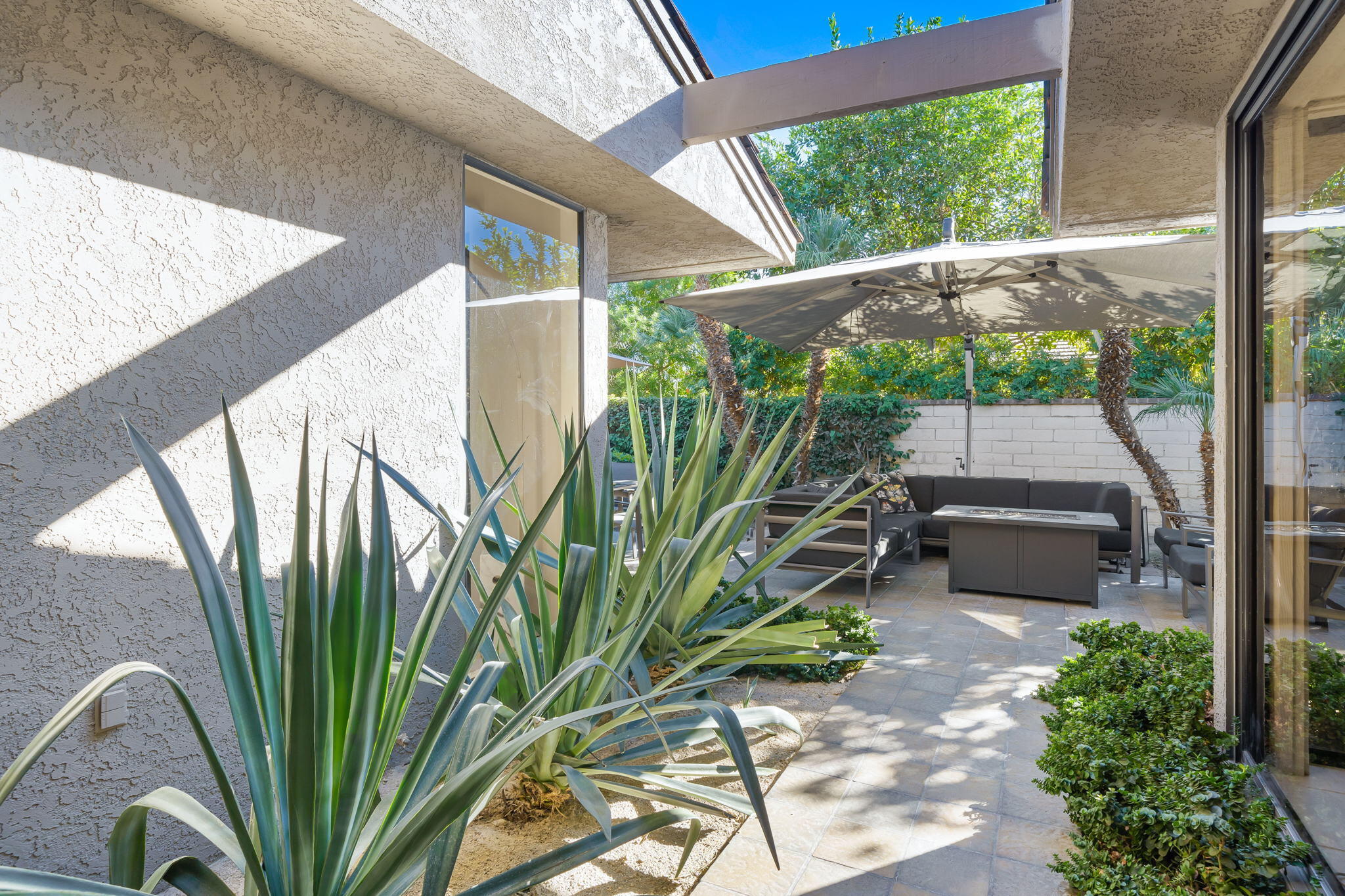 18 Lehigh Court Rancho Mirage, CA 92270 - Photo 38 of 53 a backyard of a house with table and chairs potted plants with floor to ceiling window