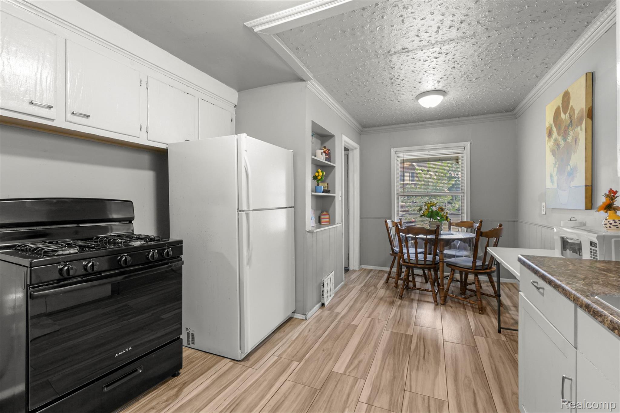 6780 Rutland Street Detroit, MI 48228 - Photo 15 of 35 White kitchen cabinetry, built-in shelving, wood-finish flooring, and crown molding