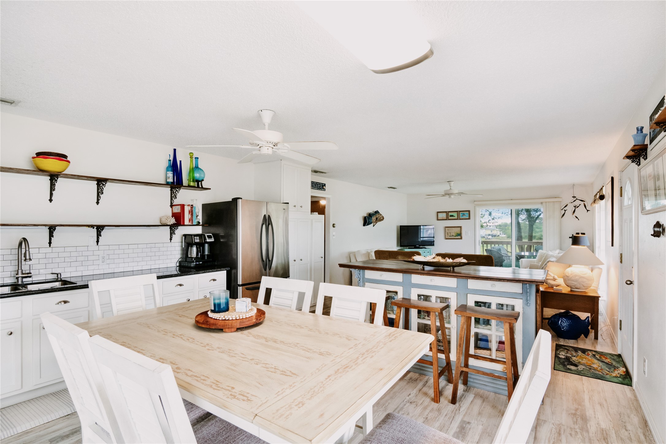 88 Bay Street Port O'Connor, TX 77982 - Photo 9 of 23 a kitchen with stainless steel appliances kitchen island granite countertop a table chairs and a refrigerator