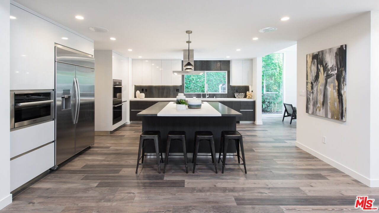 2213 Roscomare Road Los Angeles, CA 90077 - Photo 6 of 39 a dining table with stainless steel appliances kitchen island granite countertop a table chairs and a refrigerator