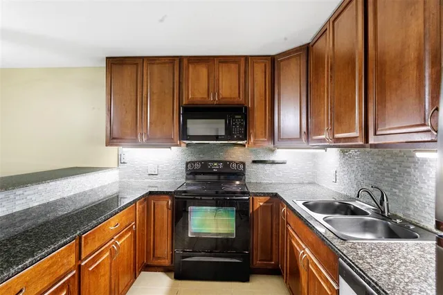 a kitchen with granite countertop wooden cabinets a stove and a sink