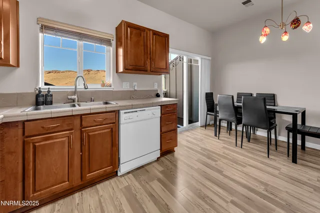 a kitchen with stainless steel appliances granite countertop a refrigerator a sink dishwasher a dining table and chairs with wooden floor