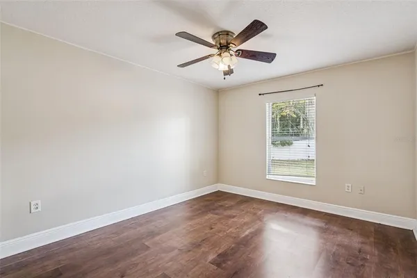 an empty room with wooden floor fan and windows
