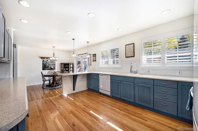 a kitchen with stainless steel appliances kitchen island granite countertop a refrigerator a stove a sink and dishwasher with wooden floor