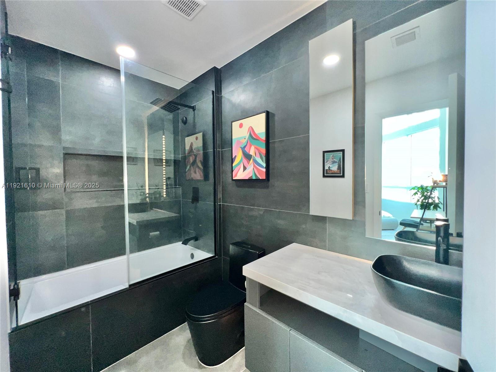 1900 North Bayshore Drive, Unit 909 Miami, FL 33132 - Photo 15 of 23 a bathroom with a sink a large mirror and a shower
