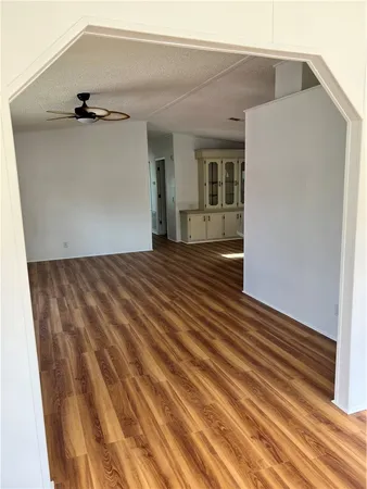 a view of a big room with wooden floor and ceiling fan