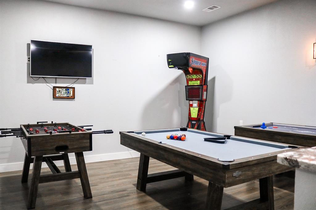 997 Ovilla Road Waxahachie, TX 75167 - Photo 7 of 32 Spacious recreation area featuring wood-finish flooring, a wall-mounted television, and a built-in stone countertop
