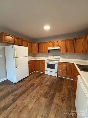 a kitchen with wooden floors and white appliances