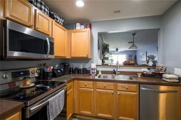 a kitchen with stainless steel appliances a sink a stove a microwave cabinets and a counter top space