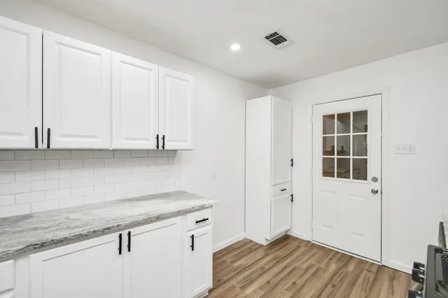a view of a kitchen with white cabinets and wooden floor
