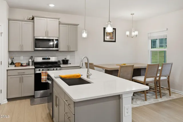 a kitchen with stainless steel appliances a stove a sink a microwave a dining table and chairs