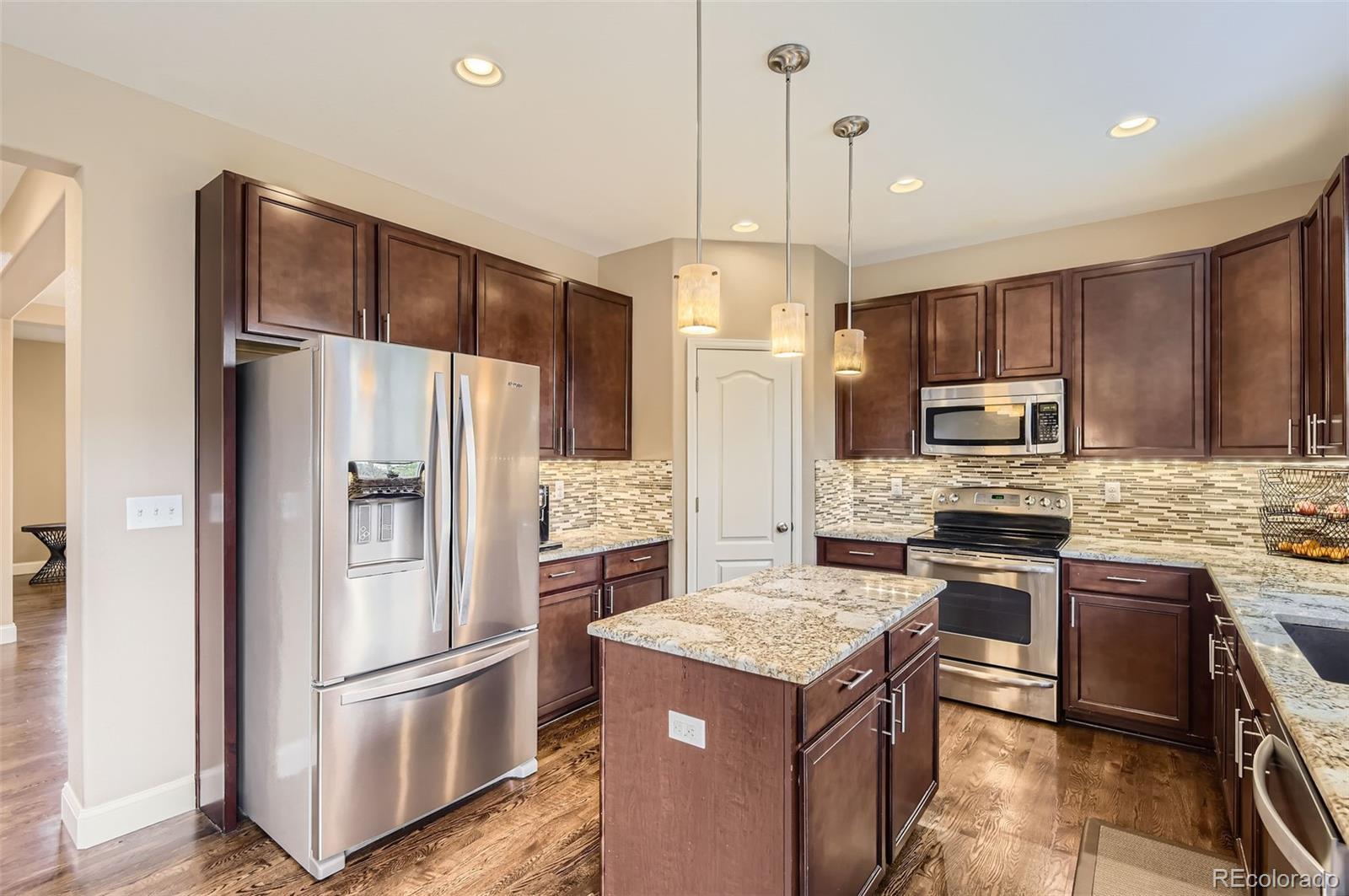 14110 Greenfield Loop Parker, CO 80134 - Photo 11 of 47 a kitchen with a refrigerator a sink and wooden cabinets